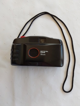 A black plastic lightweight no brand 35mm Optical Lens automatic focus camera with a black woven cotton neck cord attached with a bslck vinylcase.