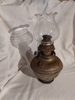 A vintage brass kerosene lamp with a clear glass chimney with frilled rim.