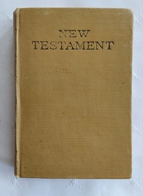 A miniature khaki leatherette covered New Testament with the title stamped in black lettering at the top of the front cover.