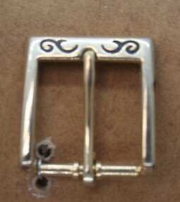 Brass half buckle with pressed swirls on bar, used on dress pieces . Imported by Holden and Frost