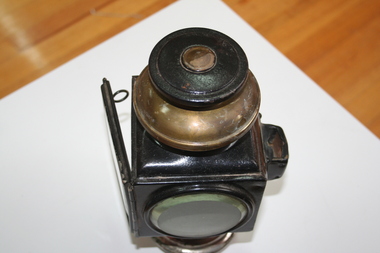 Pair of steel carriage lamps. Square lens to front (opening) and round lens to side, either left or right, Brass fixing point and chimney.