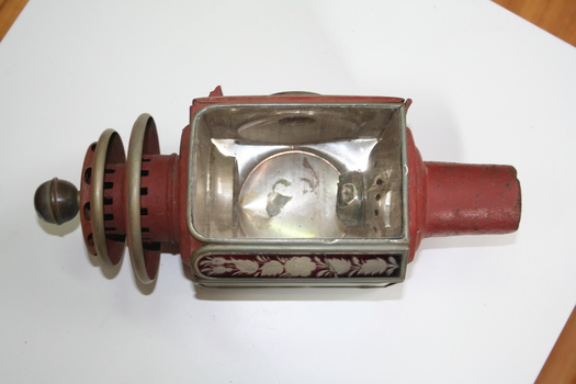 Kerosene coach lamp. Red painted. Drop down rear door with red glass circular lens.  two square glass panels with red etched floral pattern in between
