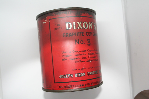 Red painted round tin with written instructions on label