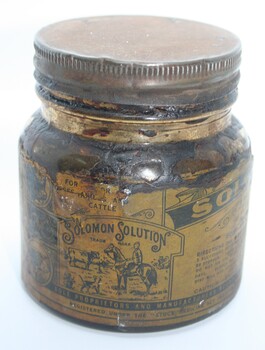squat glass screw top jar with paper label  containing salve for pain treatment