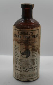 Seven sided glass bottle in amber glass, yellow paper label stating that the contents were Kendall's Spavin Treatment.
