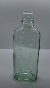 Clear glass bottle with contents and maker moulded in the front