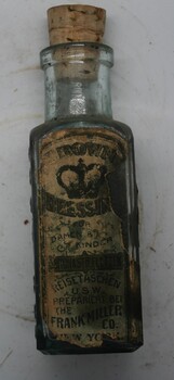 Square shaped glass jar with brown coloured label affixed that has contents printed on. Cork stopper in bottle neck.