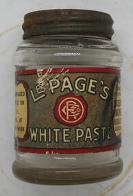 Small screw top glass jar, with paper label affixed.