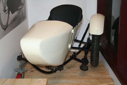 Cream coloured single seat motorcycle side car mounted on a black frame