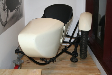 Cream coloured single seat motorcycle side car mounted on a black frame