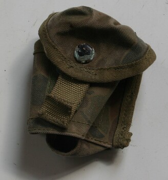 Canvas pouch painted with camouflage print steps to attach to belt