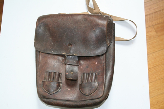 Leather shoulder bag with canvas shoulder strap. Pouches on the front for holding ammunition
