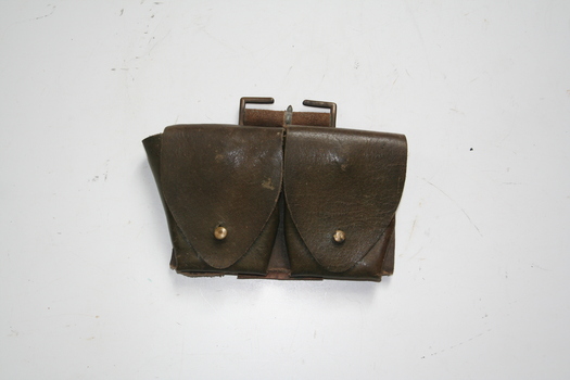 Two pouches  riveted onto a leather strap, riveted to that a leather strap with a buckle. Pouches have flaps that fix to front of pouch with a leather brass stud