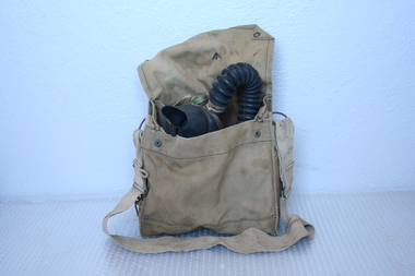 Canvas bag with webbing strap, canvas cover, with brass press studs.  Inside bag gas mask with items for maintaining the mask.