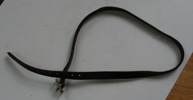 Brown leather strap, holes mid length and at the end. Brass buckle at other.