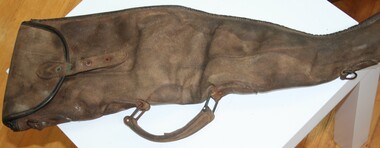 Brown leather gun carrier end opening covered by flap. Metal buckles