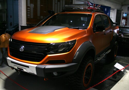 Colarado XTreme Orange/bronze body with black roof rack and roll bar. Roof rack has driving lights built in. Winch built into front bumper.