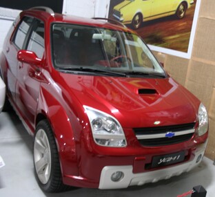 Burgundy coloured 5 door SUV with 5 spoke alloy wheels and a matt chrome roof rack