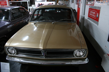 Gold coloured body, chrome bumper bar and windscreen wipers, Interior is dark coloured.