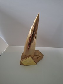 Gold plated metal trophy angled to a point on solid base