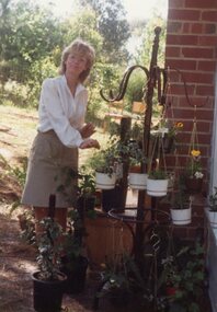 Photograph, A lady with hanging baskets at POCH, Unknown date