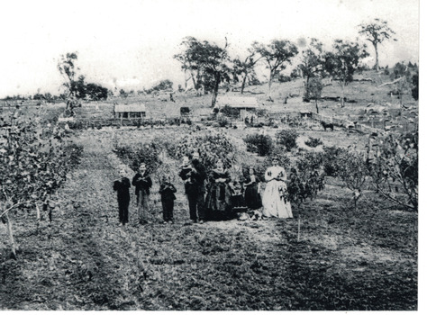 Family  of adults, children and pets standing in house yard.