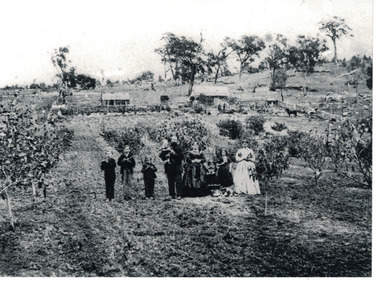 Family  of adults, children and pets standing in house yard.