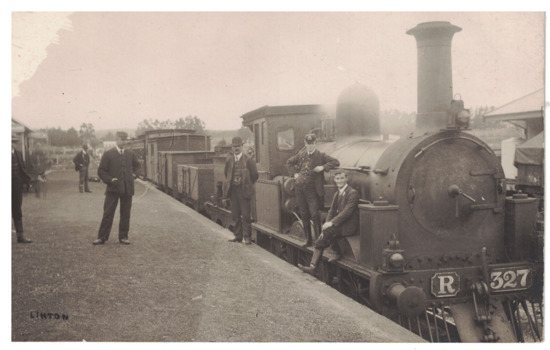 Postcard of men standing on platform beside steam engine R327 at Linton Railway station and two young men sitting on the side front platform.