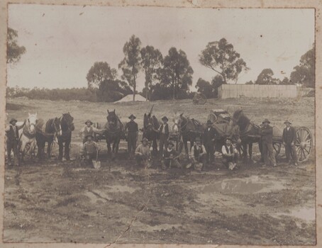 Men with horses and vehicles building dam.