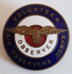 Round enameled badge with eagle in centre.