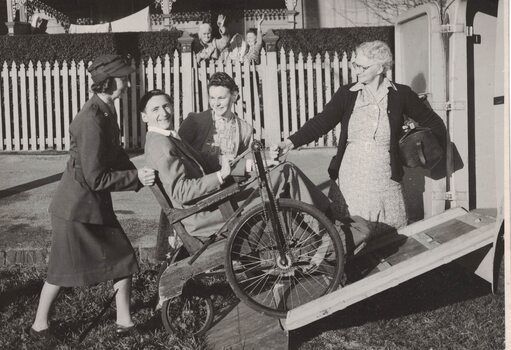 Woman pushing a wheelchair up a ramp.