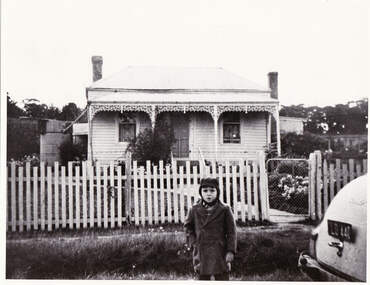 Small boy in front of a house.