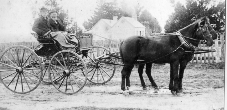 Two men in a horse drawn vehicle.