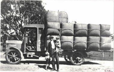 Man with two small children next to a truck.