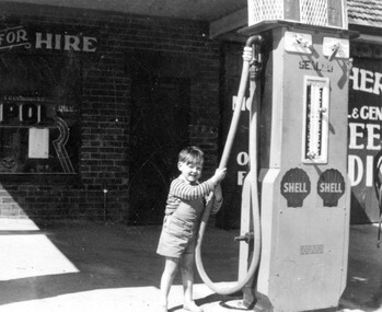 Young boy next to a petrol bowser.