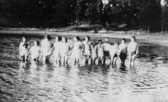 Group of children standing in water.