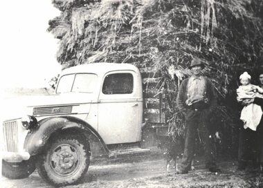 Man next to a hay laden truck.