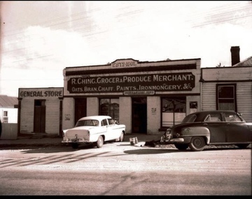 Two cars in front of a shop.