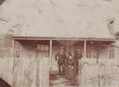 Three people in front of a house.