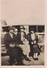 Image of three women sitting on a seat.