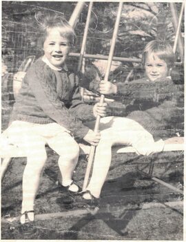 Two young girls on a swing.