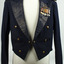 Navy blue waist length jacket with long sleeves, wide lapel and shoulder epaulets. Two brass buttons as centre fastner, with 3 brass buttons either side on front. Small medal set on right lapel with sewn ensignia badge above.