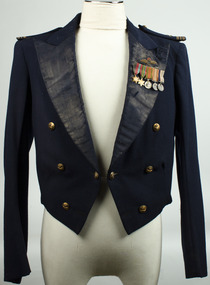 Navy blue waist length jacket with long sleeves, wide lapel and shoulder epaulets. Two brass buttons as centre fastner, with 3 brass buttons either side on front. Small medal set on right lapel with sewn ensignia badge above.