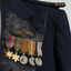 Small medal set with two gold stars and three round silver medals on striped ribbons, fastened to navy blue jacket lapel.  Embroided RAF badge sewn just above medals