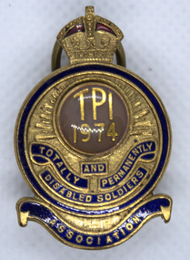 Small round gold badge with crown top and blue scroll at bottom