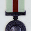 Round bronze medal with pale green and red ribbon.