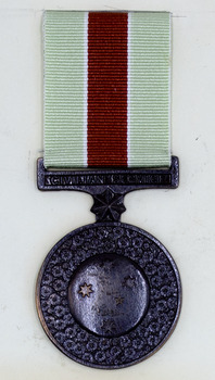 Round bronze medal with pale green and red ribbon.