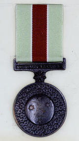 Round bronze medal with pale green and red ribbon.