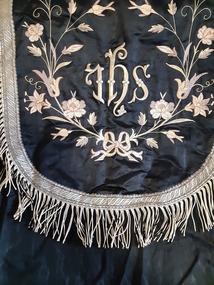 Ceremonial object - Benediction  cope, Black moire taffeta  Benediction Cope with fringed silver embroidery  edging.   IHS  and flowers  embroidery . 1Metal clasp. 123cm