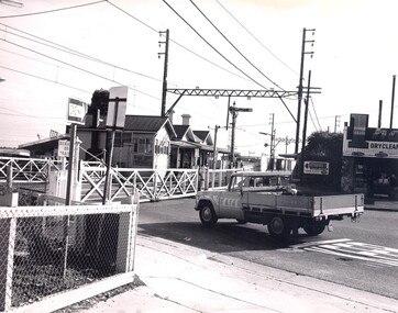 A ute is waiting to cross at the closed railway crossing gates at Highett
